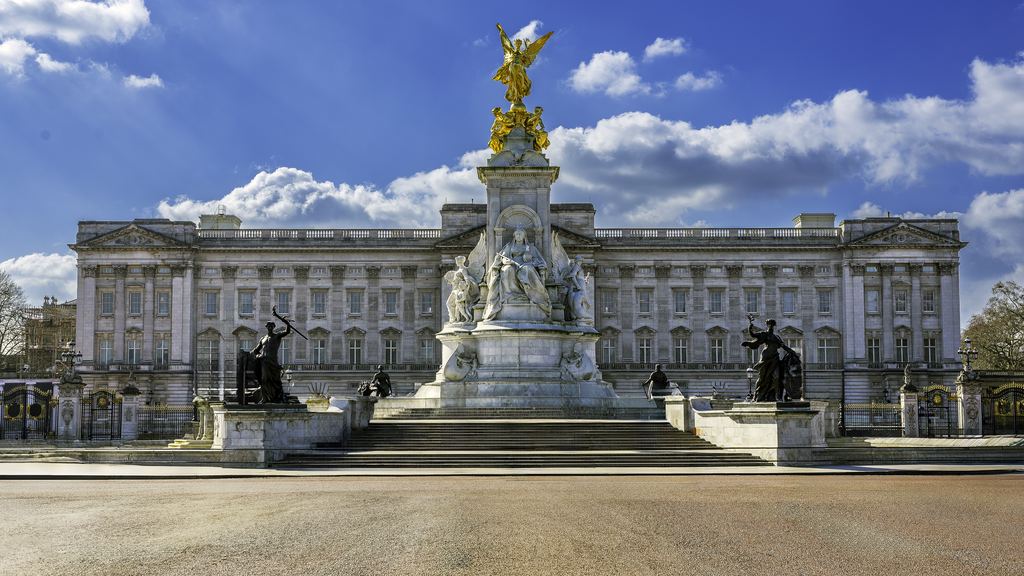 The front of Buckingham Palace behind the white marble and gold of the Victoria Memorial.