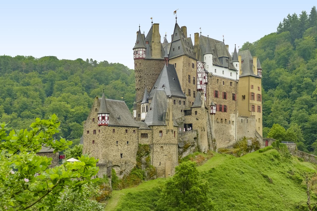 The turrets and half-timbered gables of Burg Eltz rising out of the forested valley of the Eifel in western Germany.