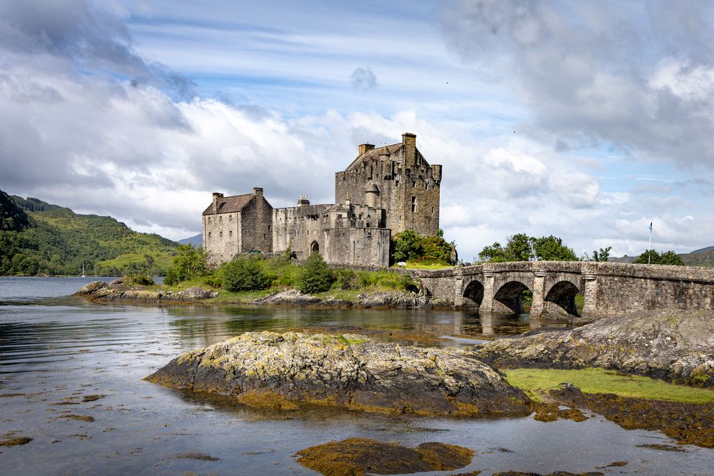 The arched stone bridge leading to Eilean Donan Castle under a heavy Highland sky.