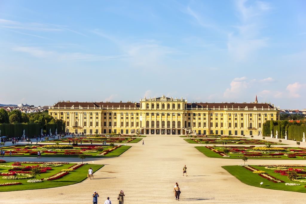 The long yellow front of Schonbrunn Palace at the end of the gravel avenue of the Great Parterre in Vienna.