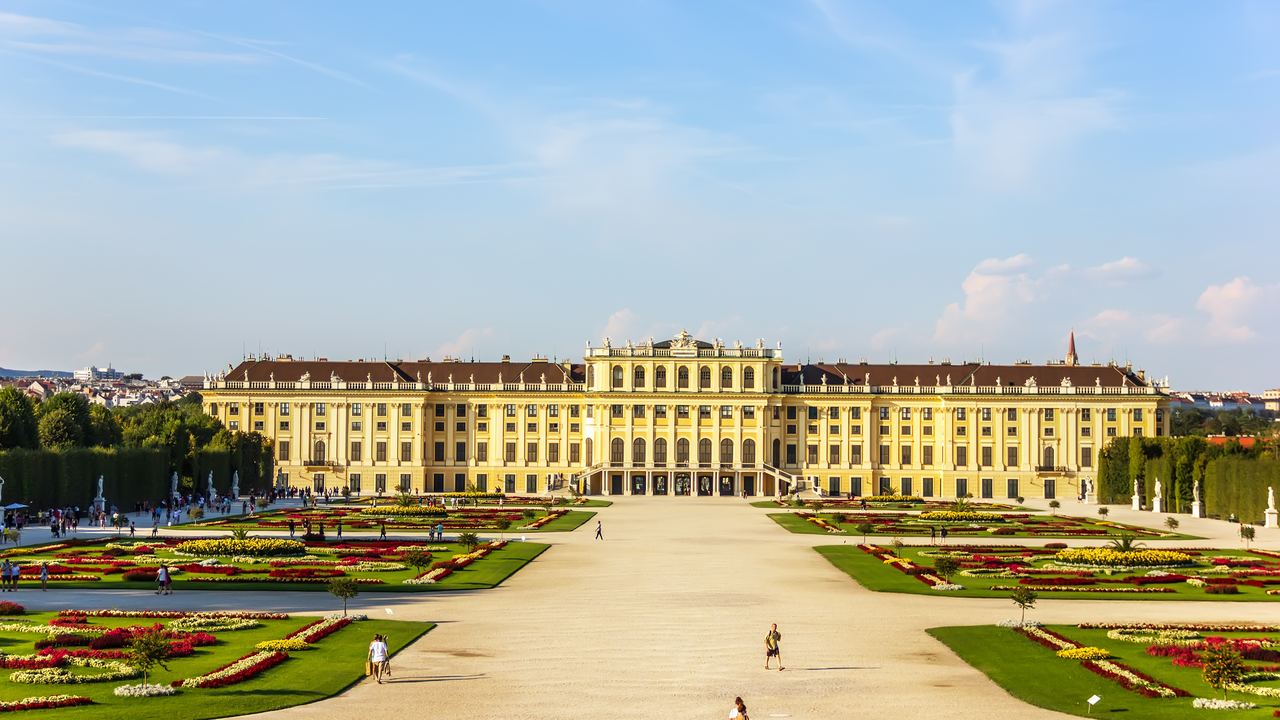 The long yellow front of Schonbrunn Palace at the end of the gravel avenue of the Great Parterre in Vienna.