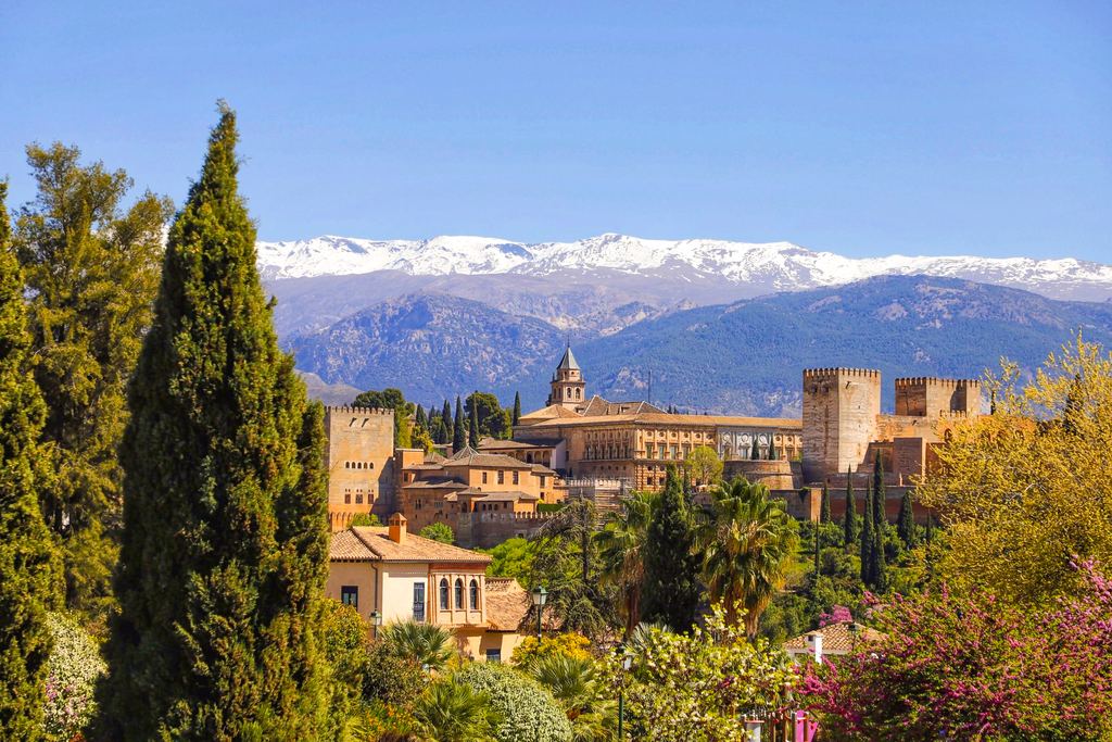 The Alhambra spread along its hill above Granada, with the snow of the Sierra Nevada behind it.