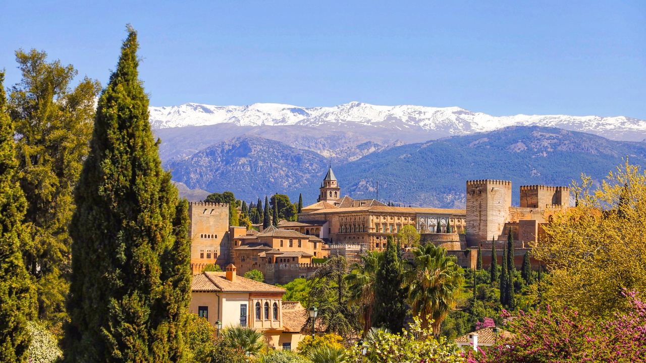 The Alhambra spread along its hill above Granada, with the snow of the Sierra Nevada behind it.