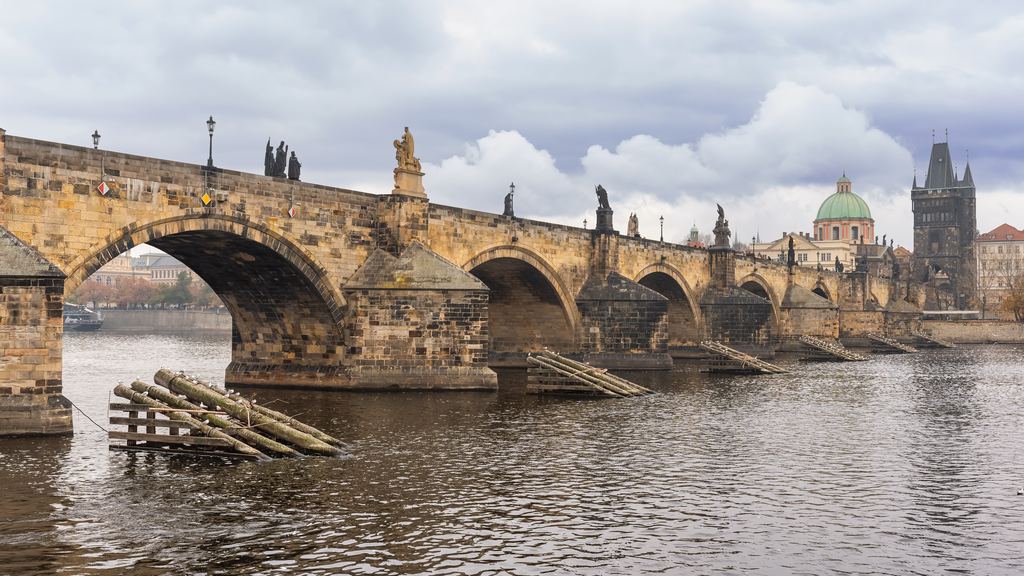 The stone arches of Charles Bridge crossing the Vltava in Prague, with the Old Town bridge tower at the far end.