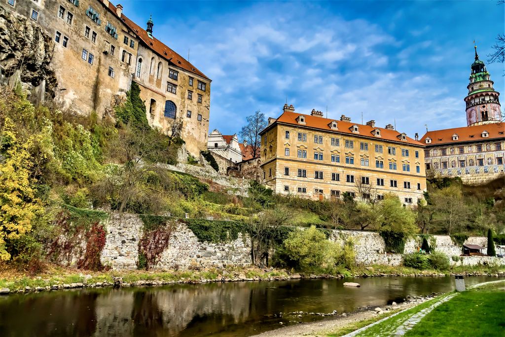 The painted walls and terraces of Cesky Krumlov castle standing on the rock above the green water of the Vltava.