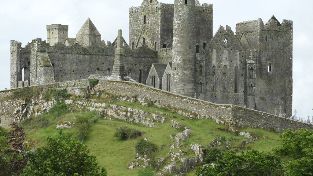 The roofless cathedral and round tower of the Rock of Cashel rising from their grassy outcrop above County Tipperary.