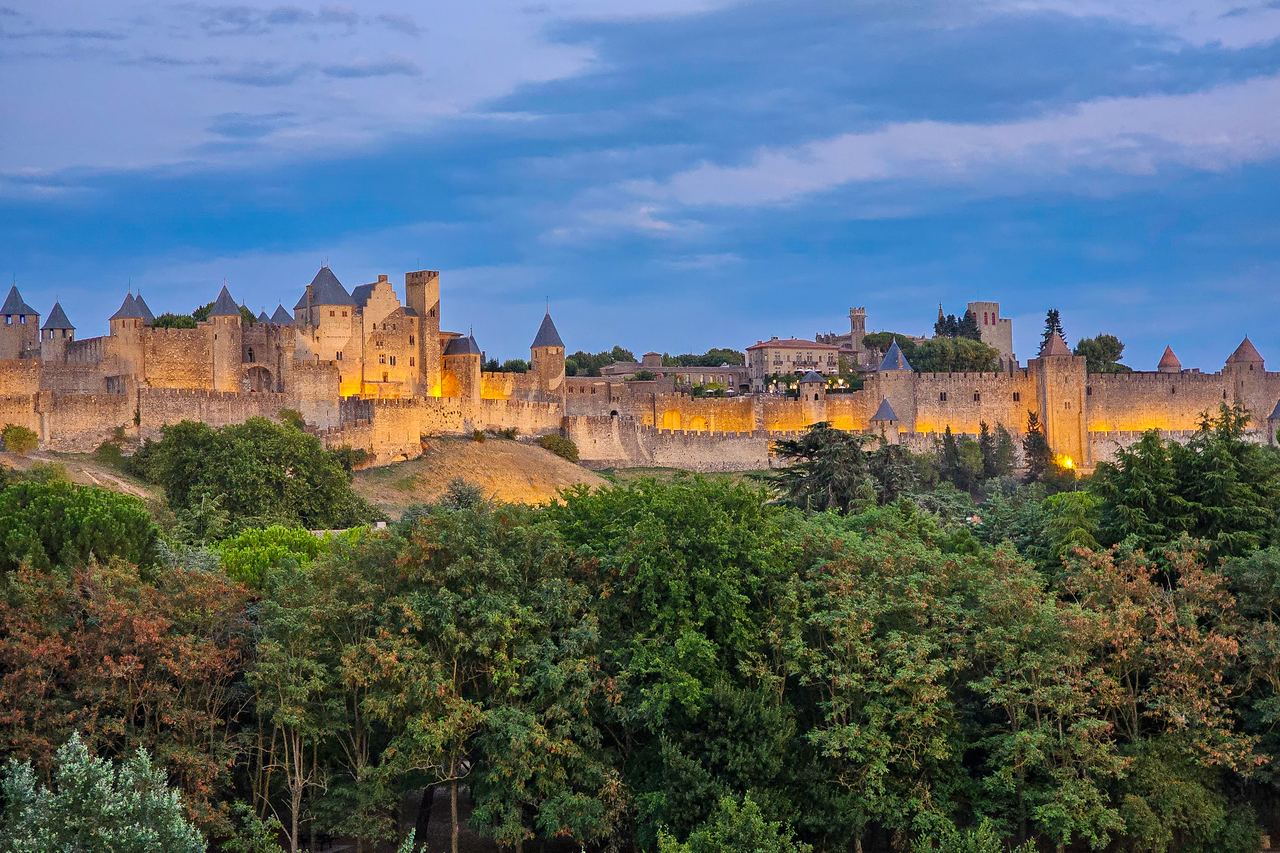 The floodlit ramparts and towers of the walled city of Carcassonne in southern France at dusk.