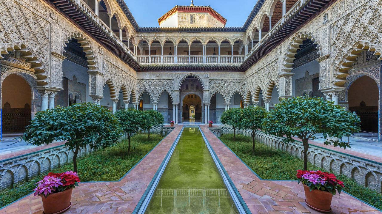 The arcades and sunken pool of the Courtyard of the Maidens in the Royal Alcazar of Seville.