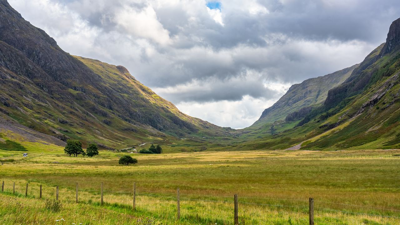 The green floor of the Glencoe valley running between steep Highland ridges under a broken sky.