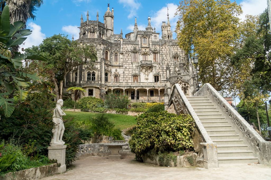 The Regaleira palace at Sintra behind its garden staircase and statue, framed by the autumn trees of the estate.