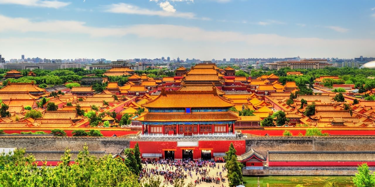 The golden roofs of the Forbidden City seen in a long line from Jingshan hill, with modern Beijing hazy behind.