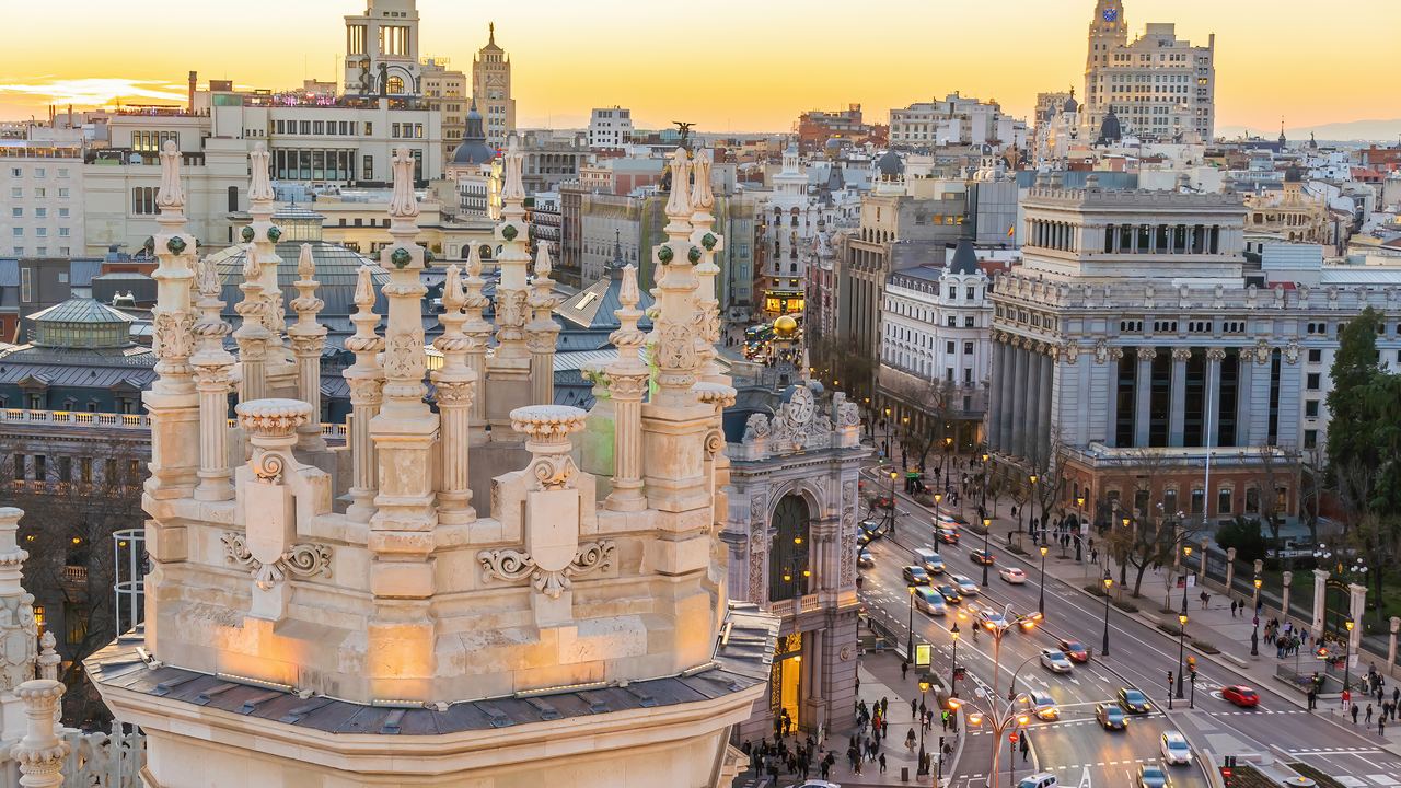 The roofs and towers of central Madrid stretching toward the Gran Via under a warm evening sky.