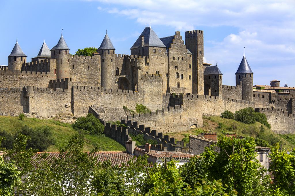 The double ring of walls and conical towers of the medieval city of Carcassonne in daylight.