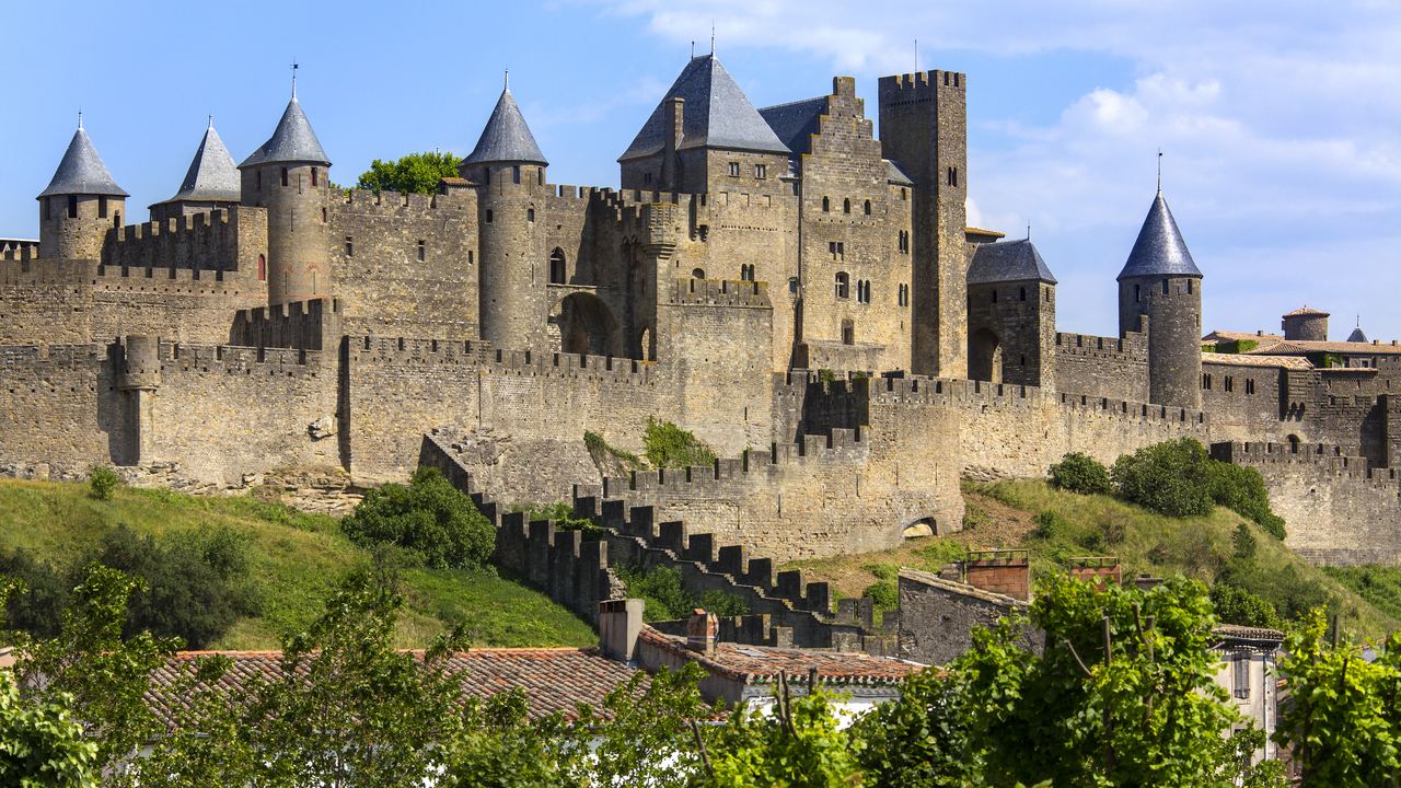 The double ring of walls and conical towers of the medieval city of Carcassonne in daylight.