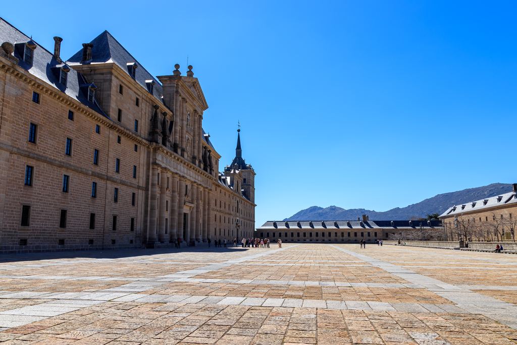 The plain granite walls and courtyard of El Escorial with the Guadarrama mountains behind.