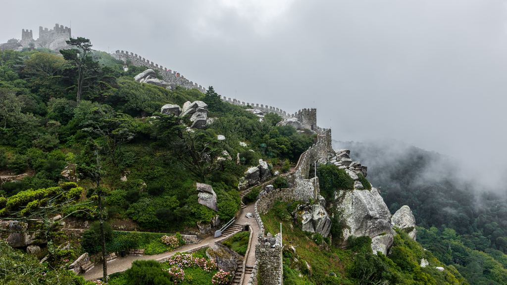The wall of the Moorish castle at Sintra climbing the wooded ridge, its towers half lost in low cloud.