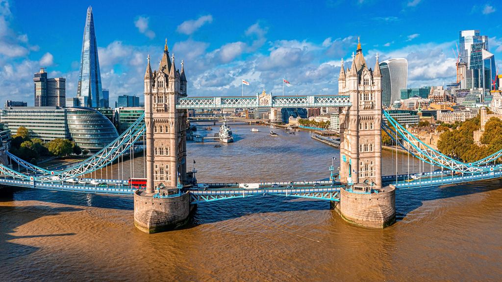 Aerial view along the River Thames with Tower Bridge in the foreground and the City of London beyond.