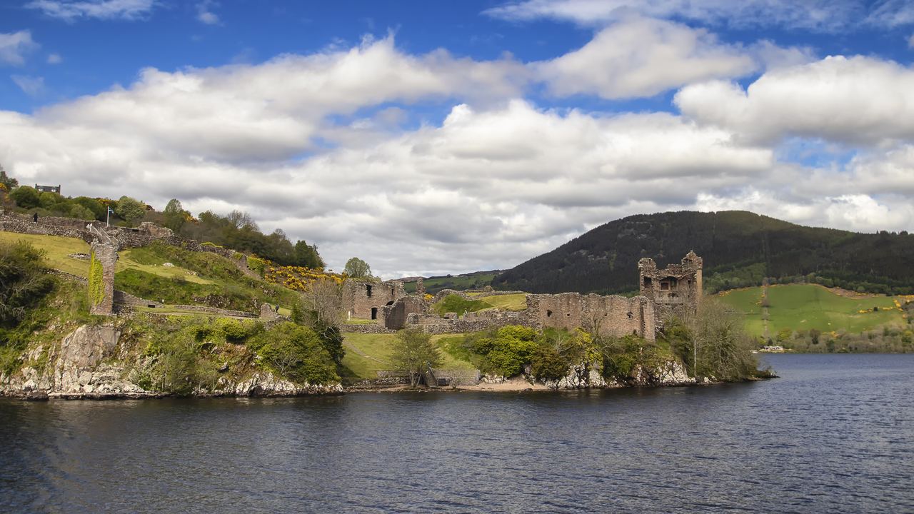 The ruins of Urquhart Castle standing on their headland above the dark water of Loch Ness.